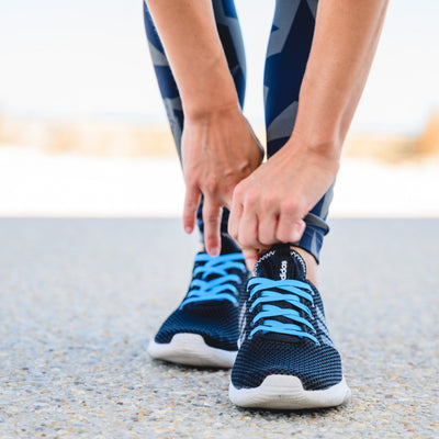 sportwoman bending over pulling on her sneakers with synxlace no tie laces, easy to fit, durable elastic, wide range of colours, suitable for everyone of any age and for all activities including running, cycling, hiking and walking